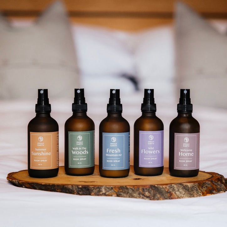 Five bottles of diffuser on a wooden tray with a blurred bed background