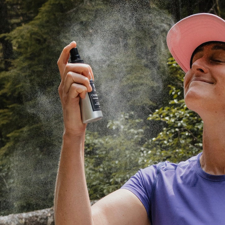 Person applying a spray product outdoors with trees in the background