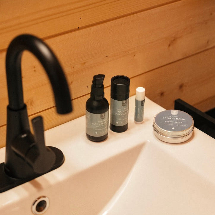 Bathroom sink with skincare products against a wooden wall.