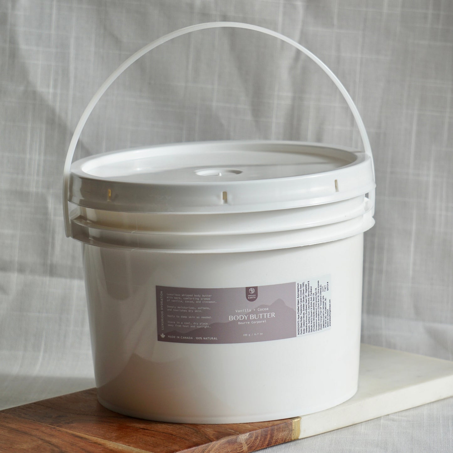 White bucket with a label on a wooden board against a gray fabric background