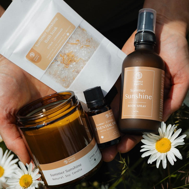 Hand holding a bottle labeled 'Sunshine' with other natural products and flowers on a grassy background
