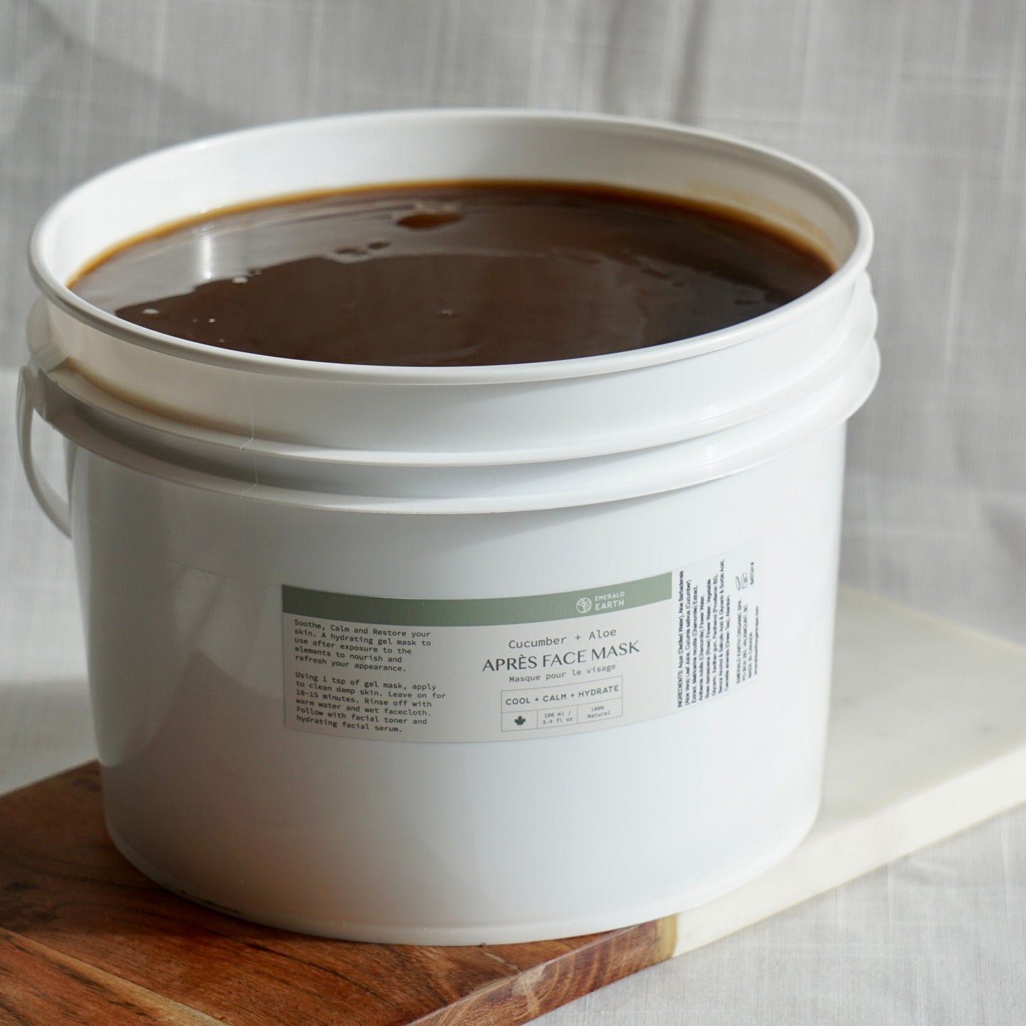 White bucket filled with dark liquid on a wooden board with a white background