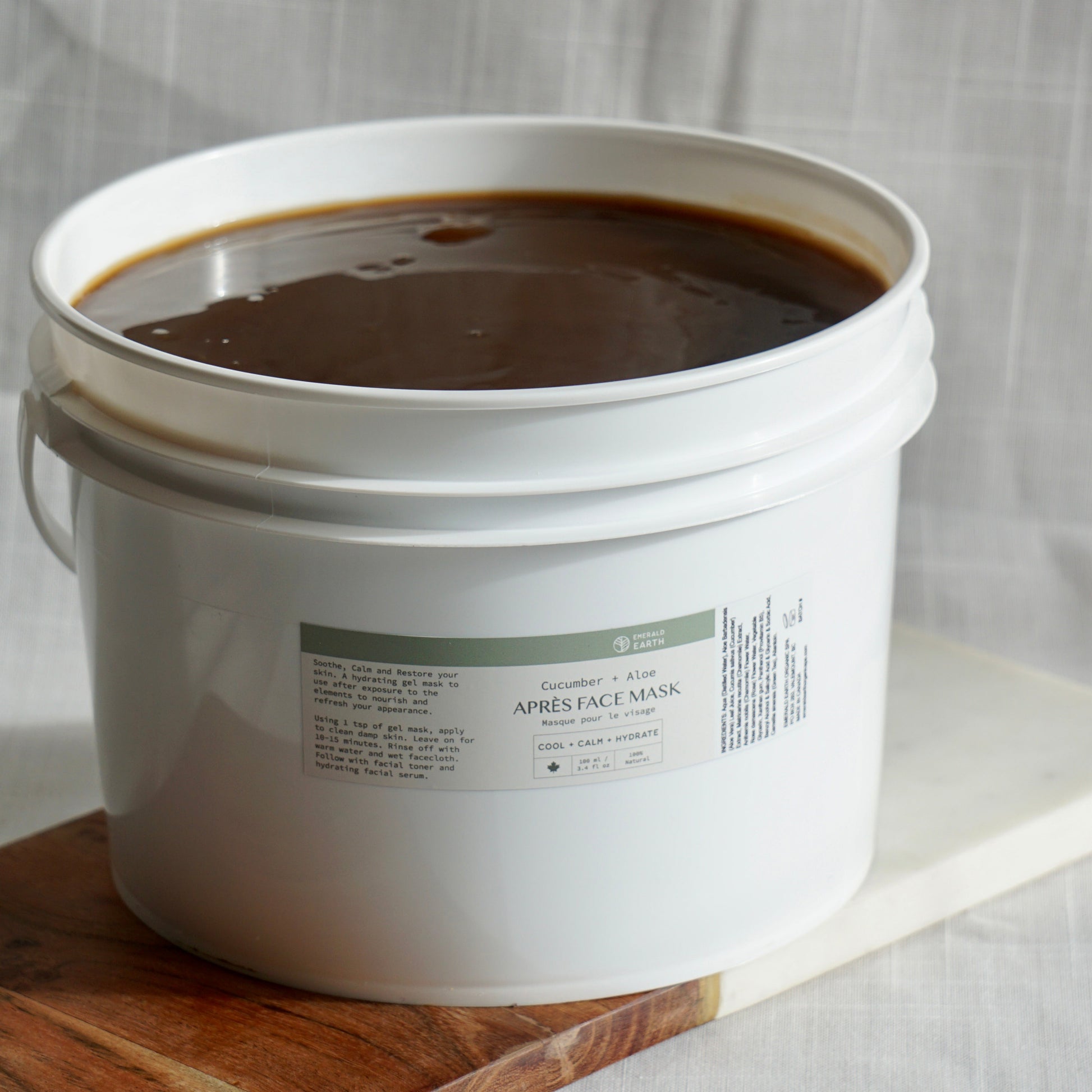 White bucket filled with dark liquid on a wooden board with a white background
