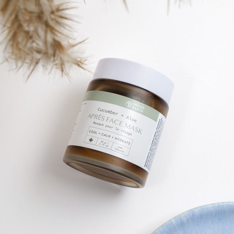Jar of cucumber and aloe vera face mask on a white surface with dried plants in the background
