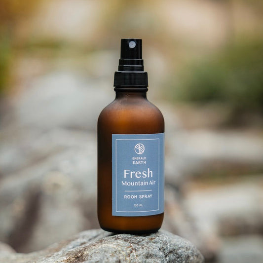 Brown spray bottle labeled 'Fresh Mountain Air' on a rock with a blurred natural background