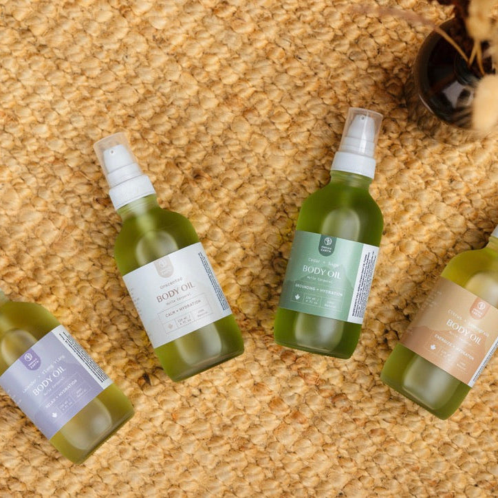 Four green bottles with white labels on a textured beige surface
