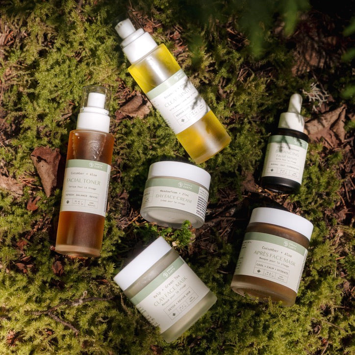 Collection of skincare products on a mossy surface with green foliage.