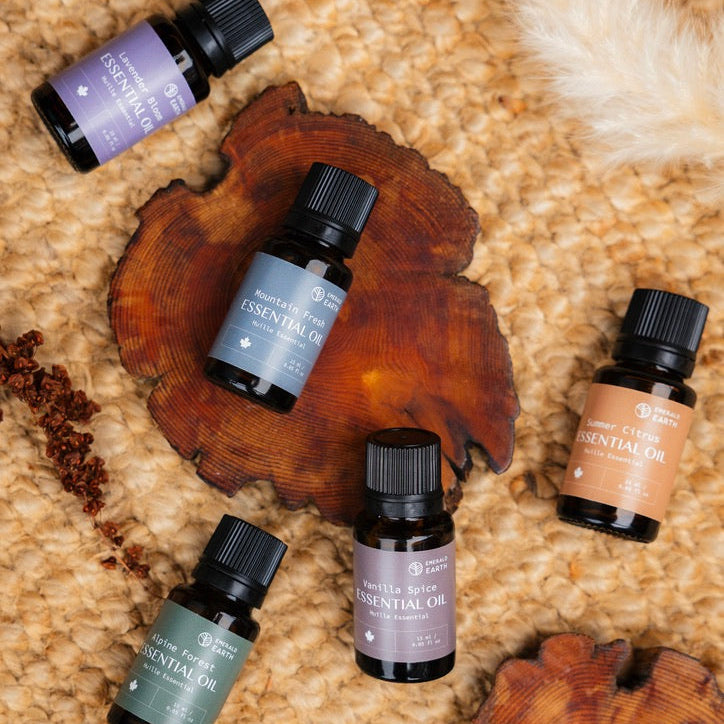 Five essential oil bottles on a textured surface with wooden elements
