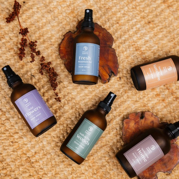 Five brown glass bottles with labels on a textured beige surface