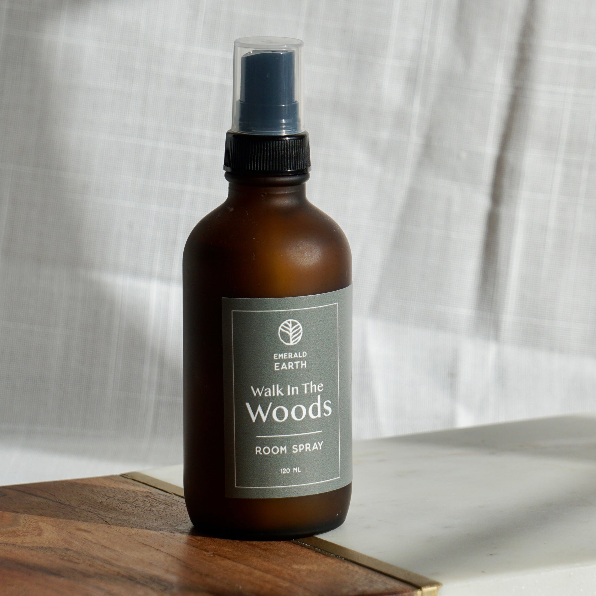 Brown spray bottle labeled 'Walk in the Woods' on a wooden board with a white fabric background