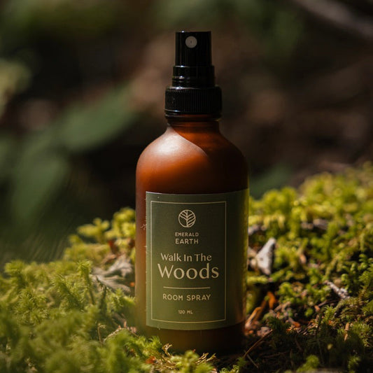 Room spray bottle labeled 'Walk In The Woods' by Emerald Earth on a mossy background