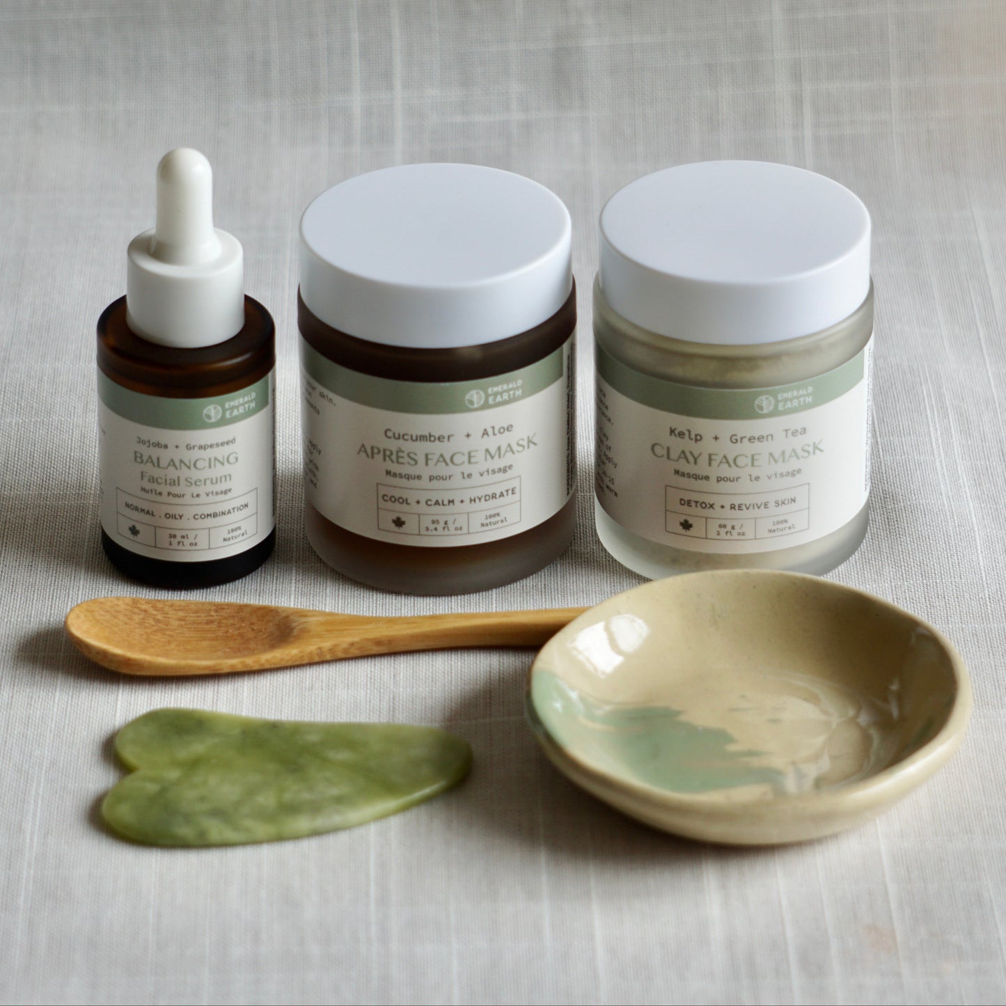 Skincare products including a dropper, jars, and a spoon on a textured surface