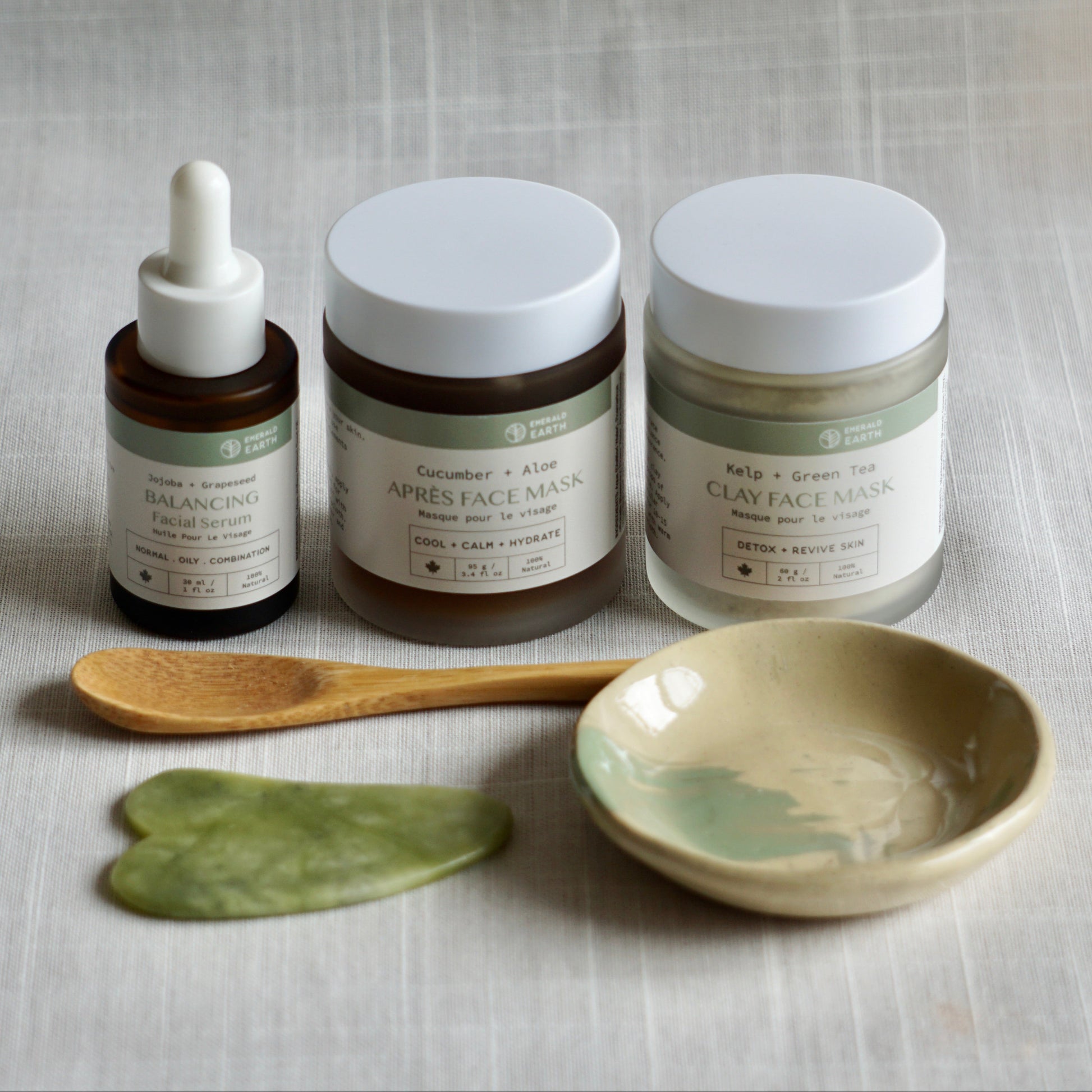 Skincare products including a dropper, jars, and a spoon on a textured surface