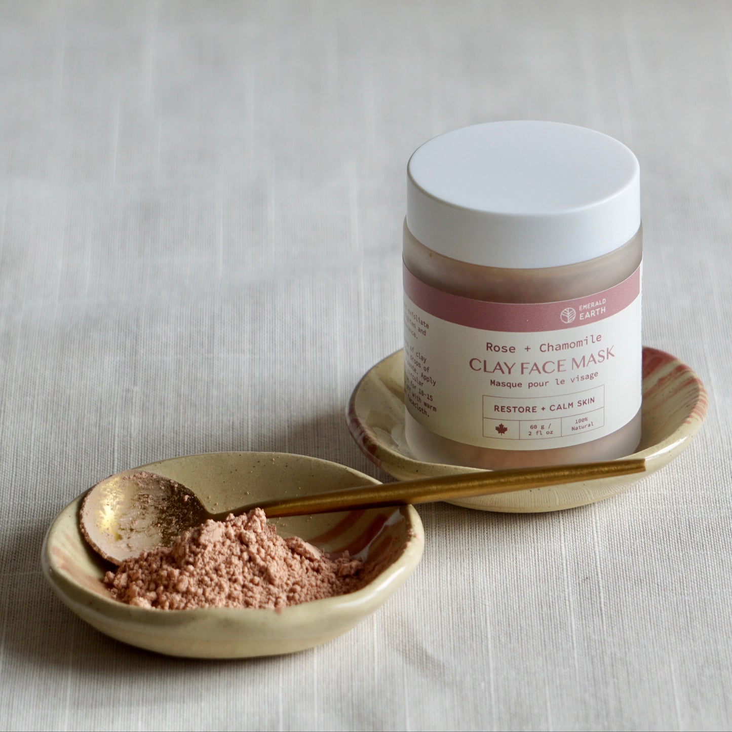 Jar of clay face mask with a spoonful of powder on a neutral background