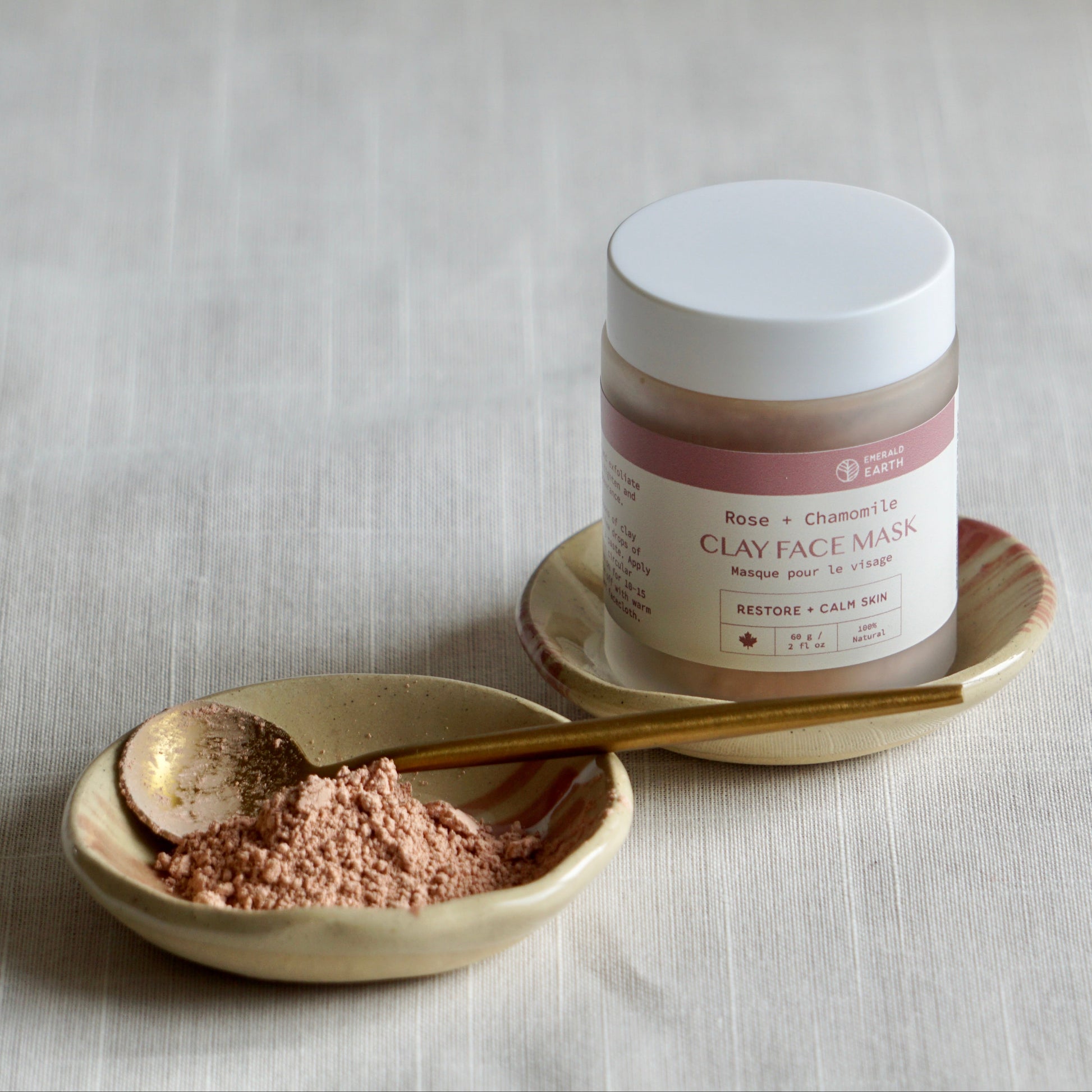 Jar of clay face mask with a spoonful of powder on a neutral background