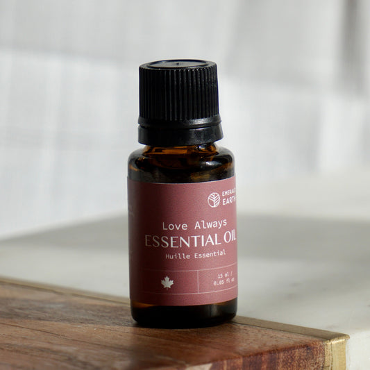 Essential oil bottle labeled 'Love Always' on a wooden surface with a neutral background