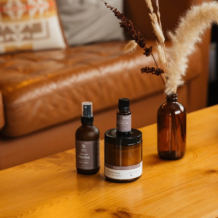 Three brown bottles on a wooden table with a blurred sofa and pillows in the background