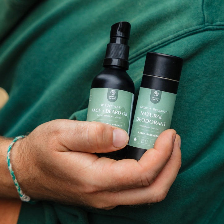 Two bottles of natural skincare products held by a person wearing a green shirt.