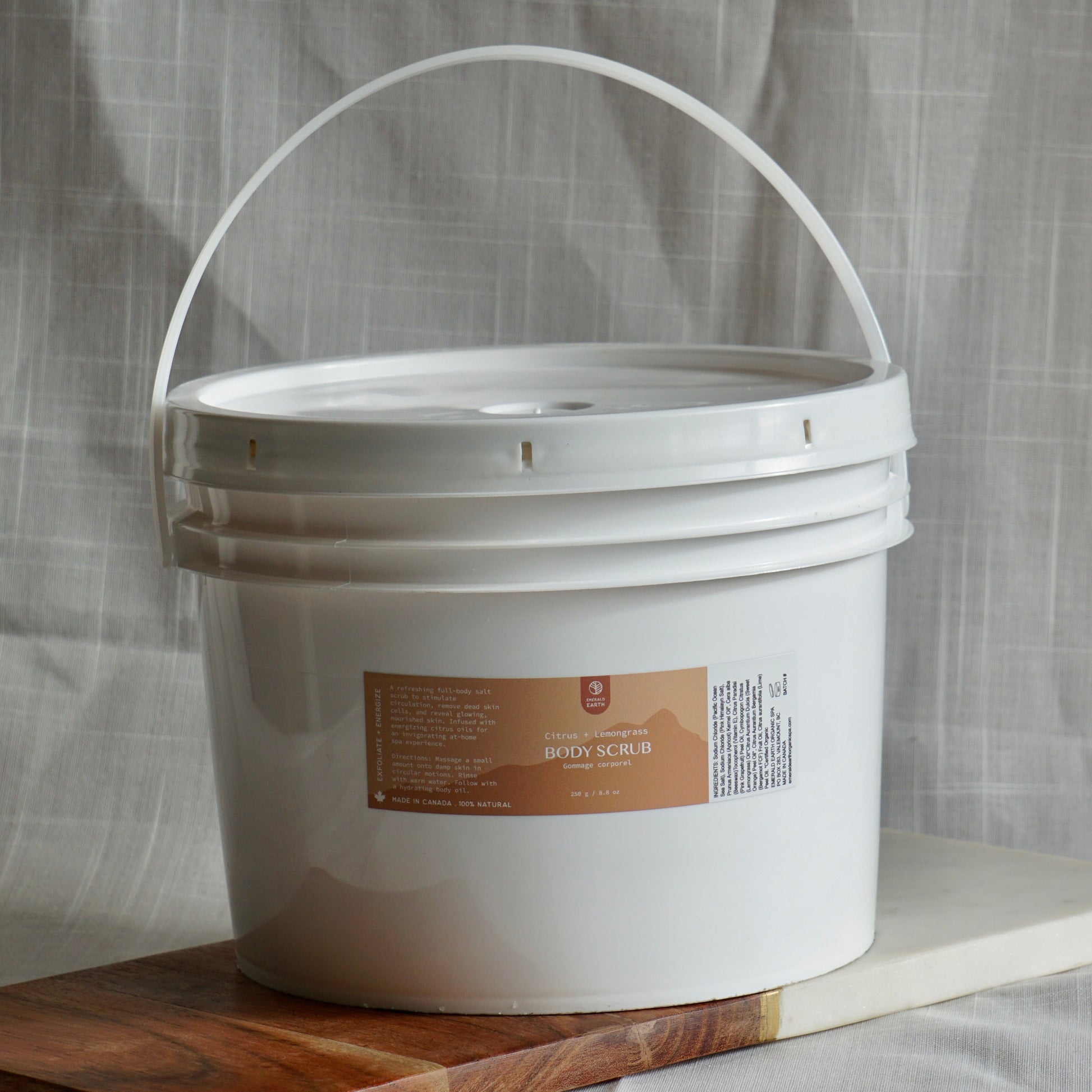 White bucket with a label on a wooden board against a textured gray background