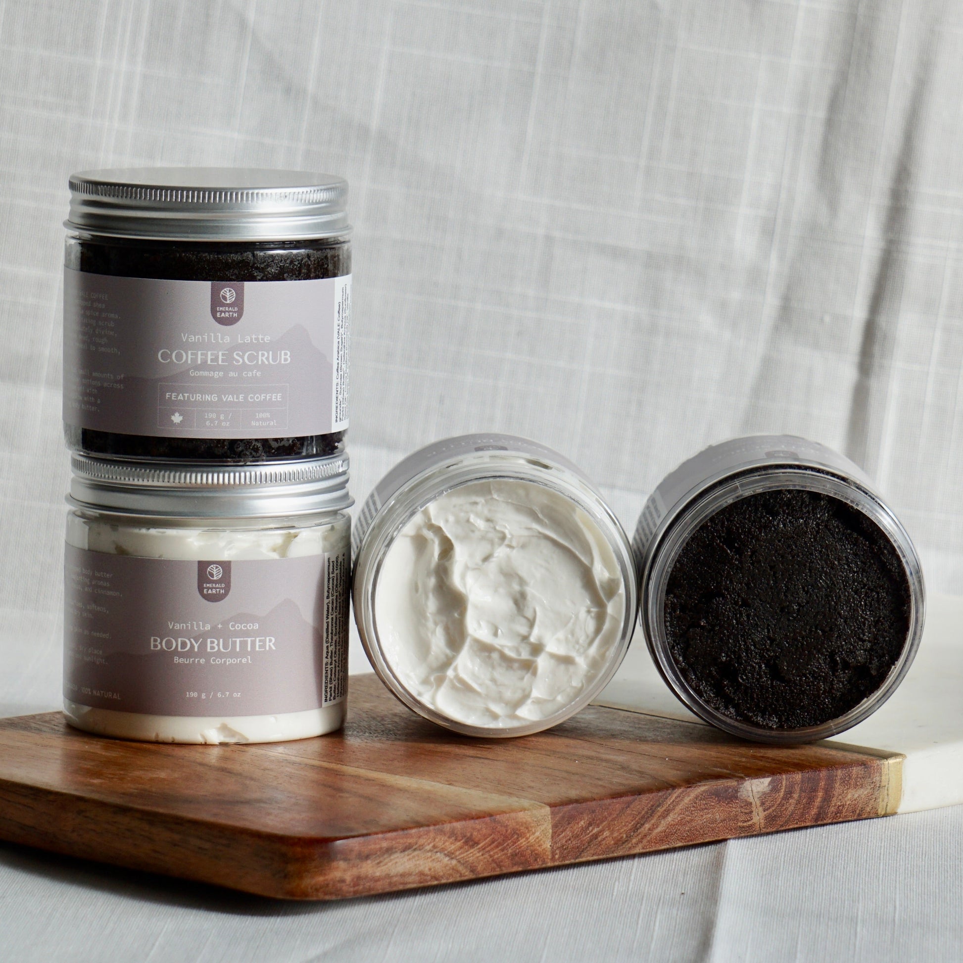 Three skincare products on a wooden tray with a gray fabric background