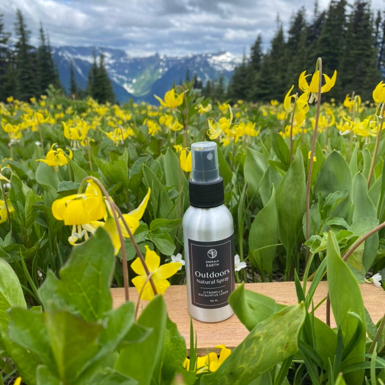 Bottle of outdoor spray in a field of yellow flowers with mountains in the background