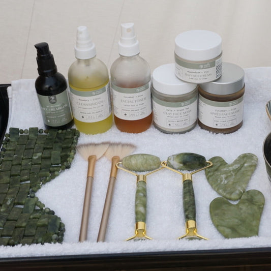 Collection of skincare products and tools on a tray with a white background