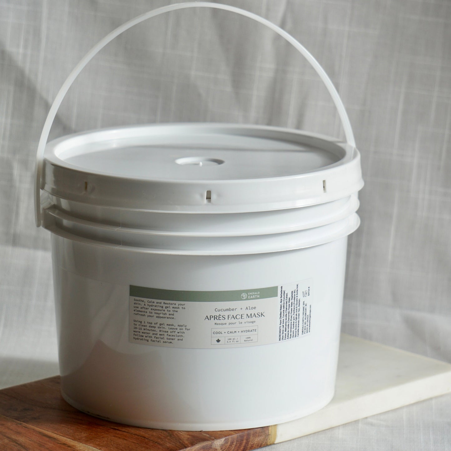 White bucket with a label on a wooden surface and light gray background