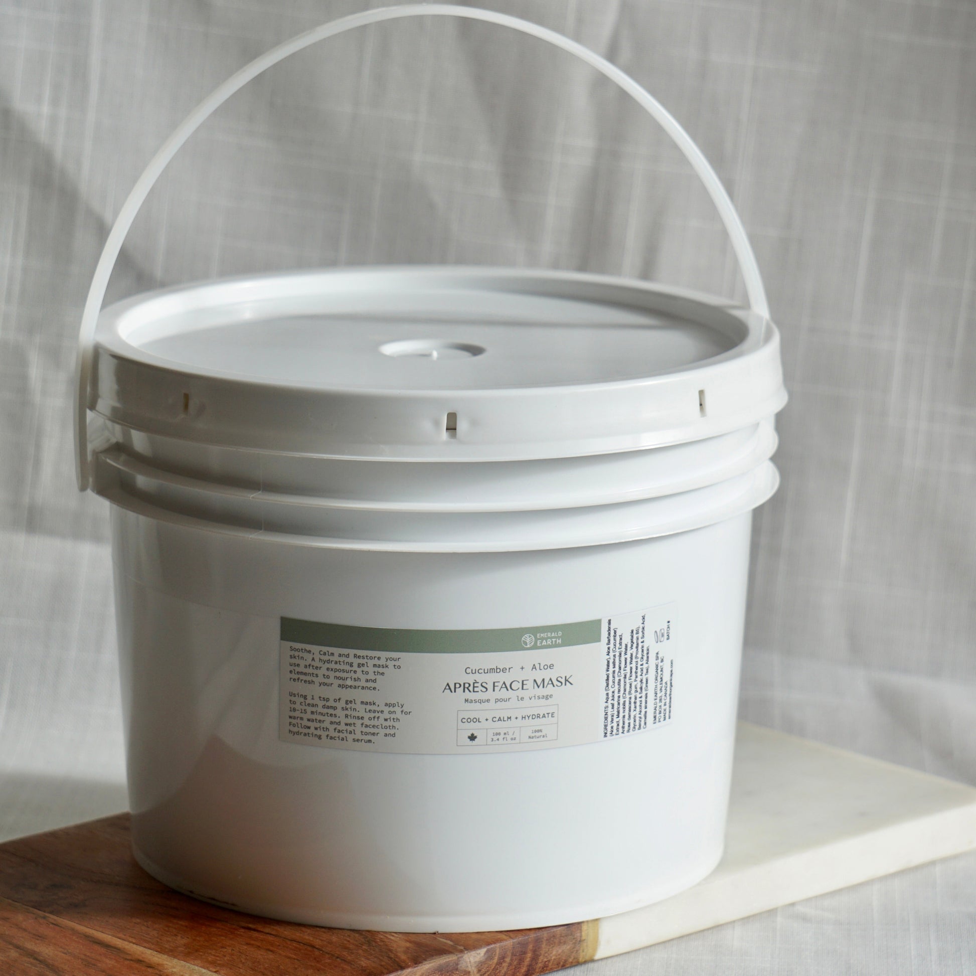 White bucket with a label on a wooden surface and light gray background