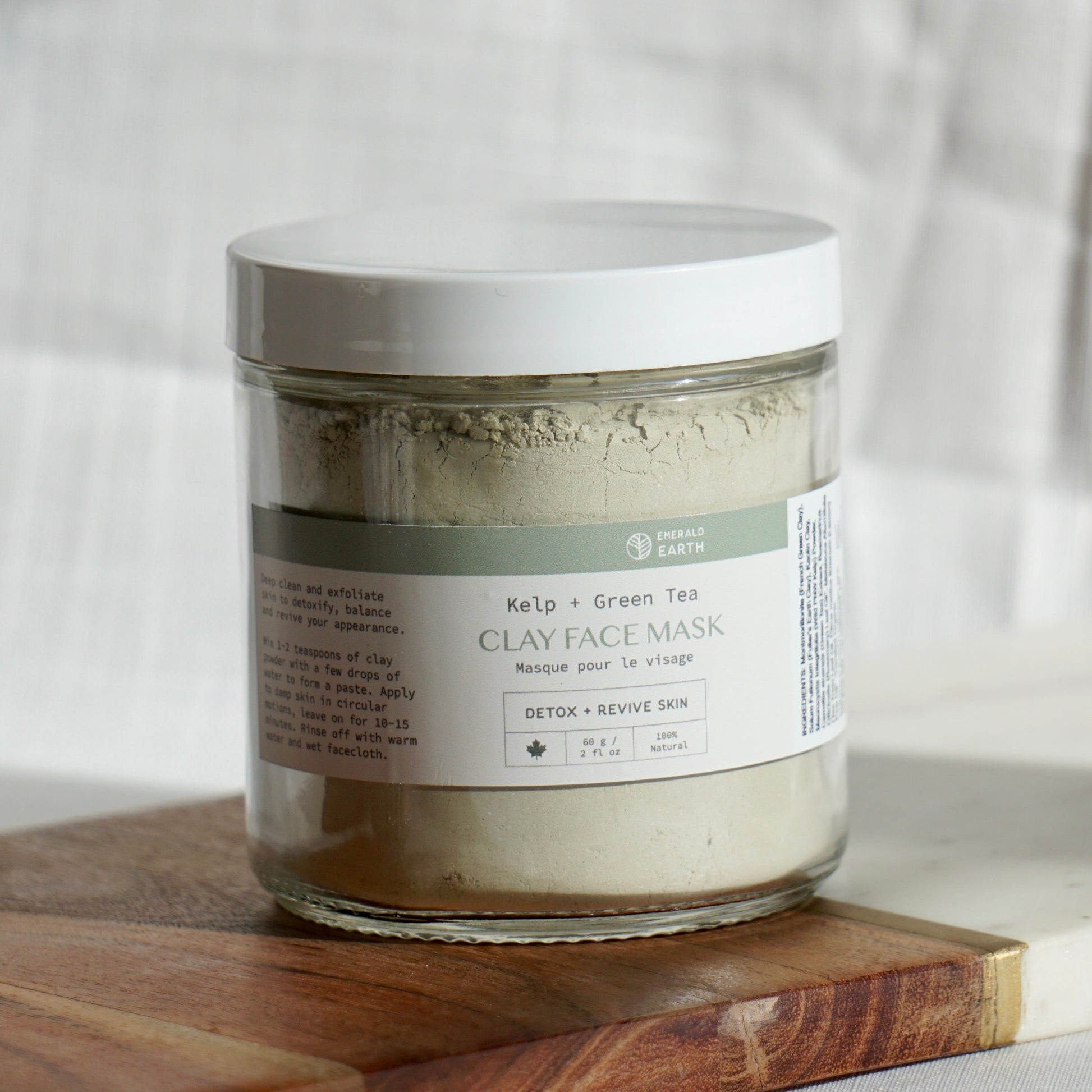 Jar of clay face mask on a wooden board with a neutral background