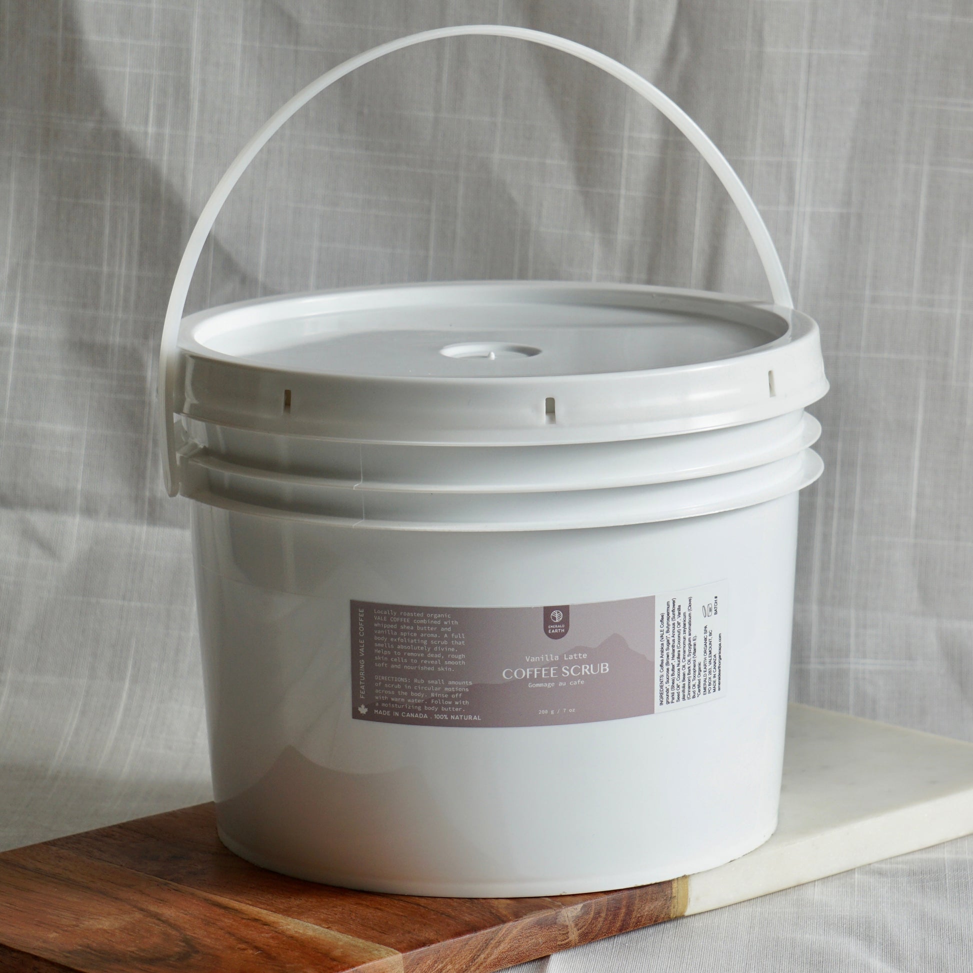 White bucket with a label on a wooden board against a light gray curtain background