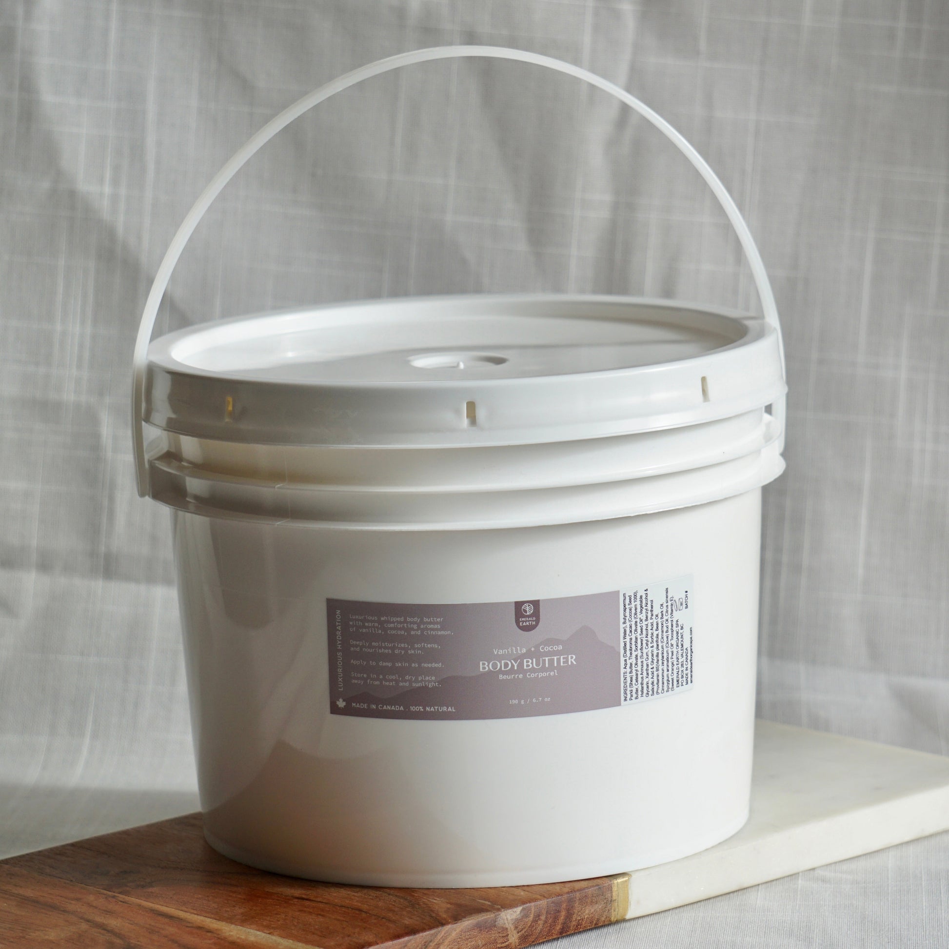 White bucket with a label on a wooden board against a gray fabric background