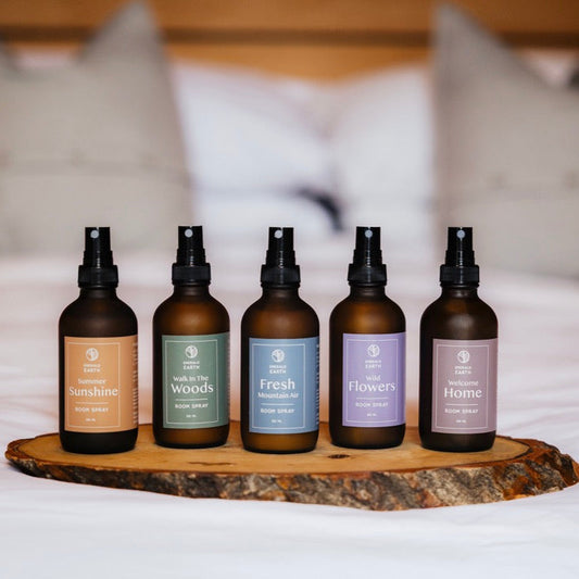 Five bottles of diffuser on a wooden tray with a blurred bed background
