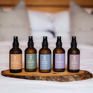 Five bottles of diffuser on a wooden tray with a blurred bed background