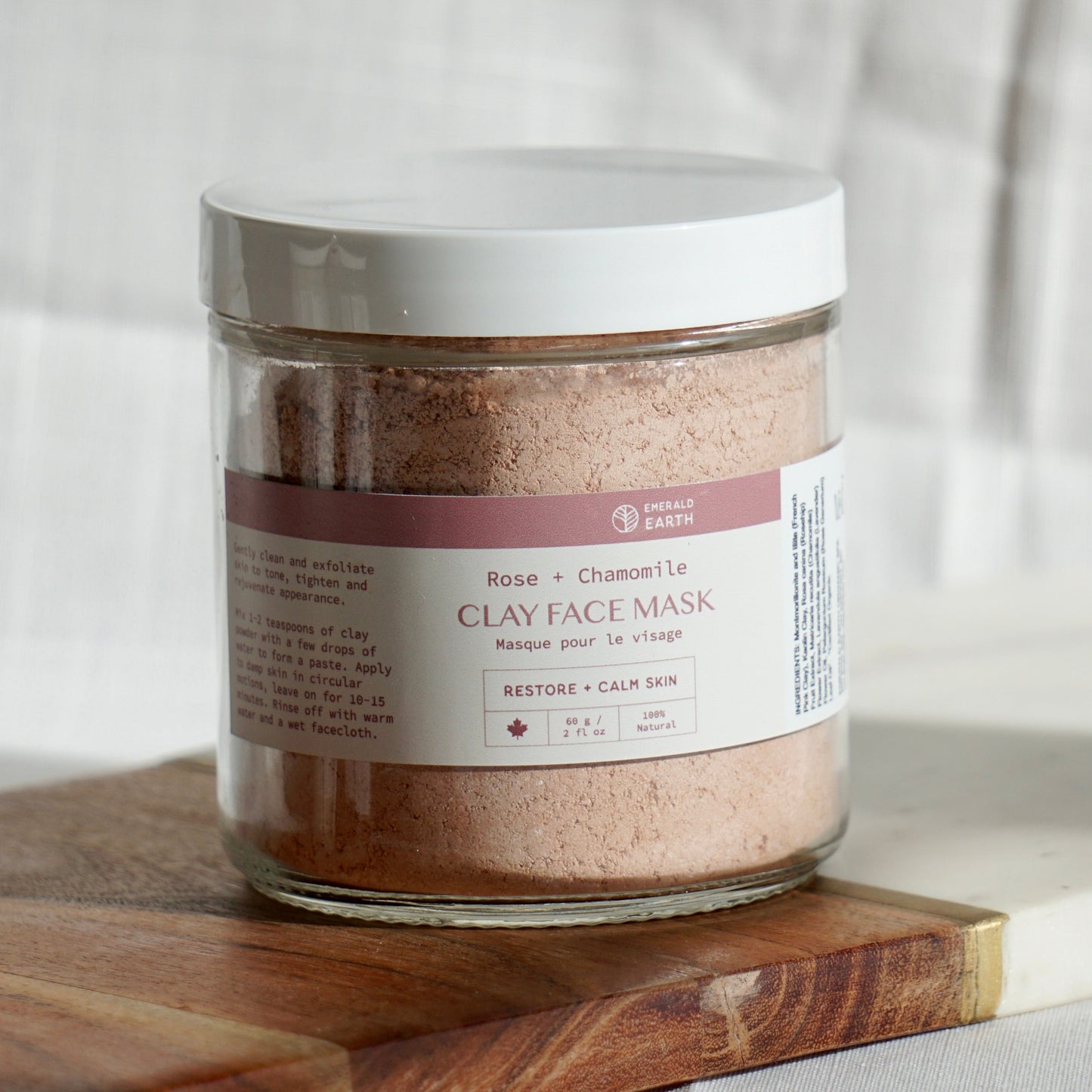 Jar of clay face mask on a wooden board with a neutral background