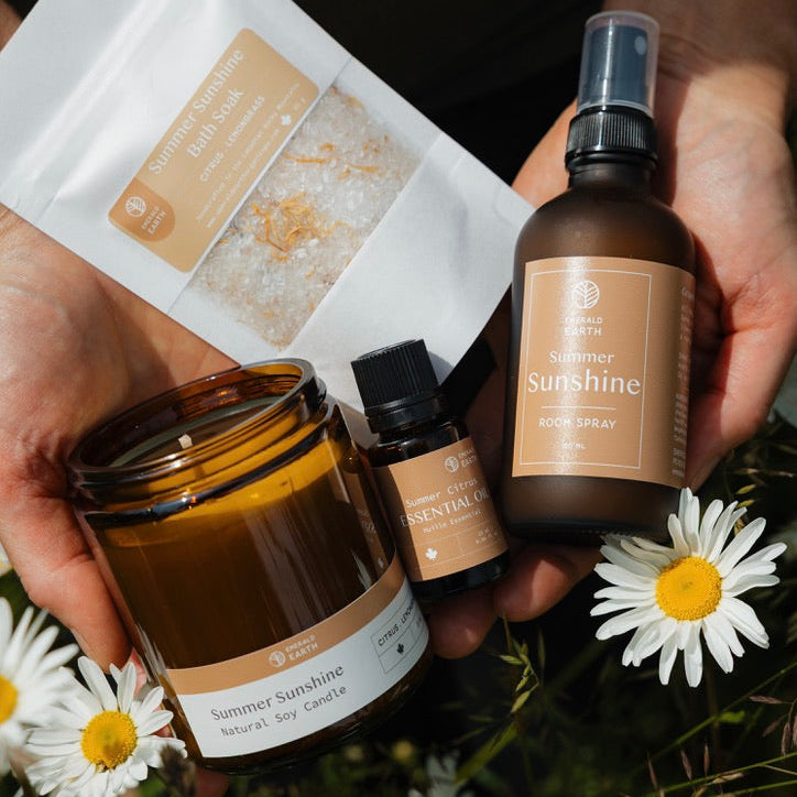 Hand holding a bottle labeled 'Sunshine' with other skincare products and flowers on a natural background