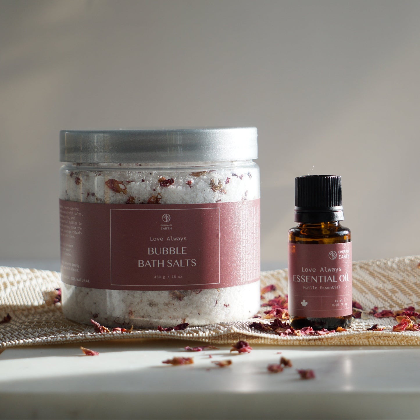 Jar of bath salts and bottle of essential oil on a textured surface with a neutral background