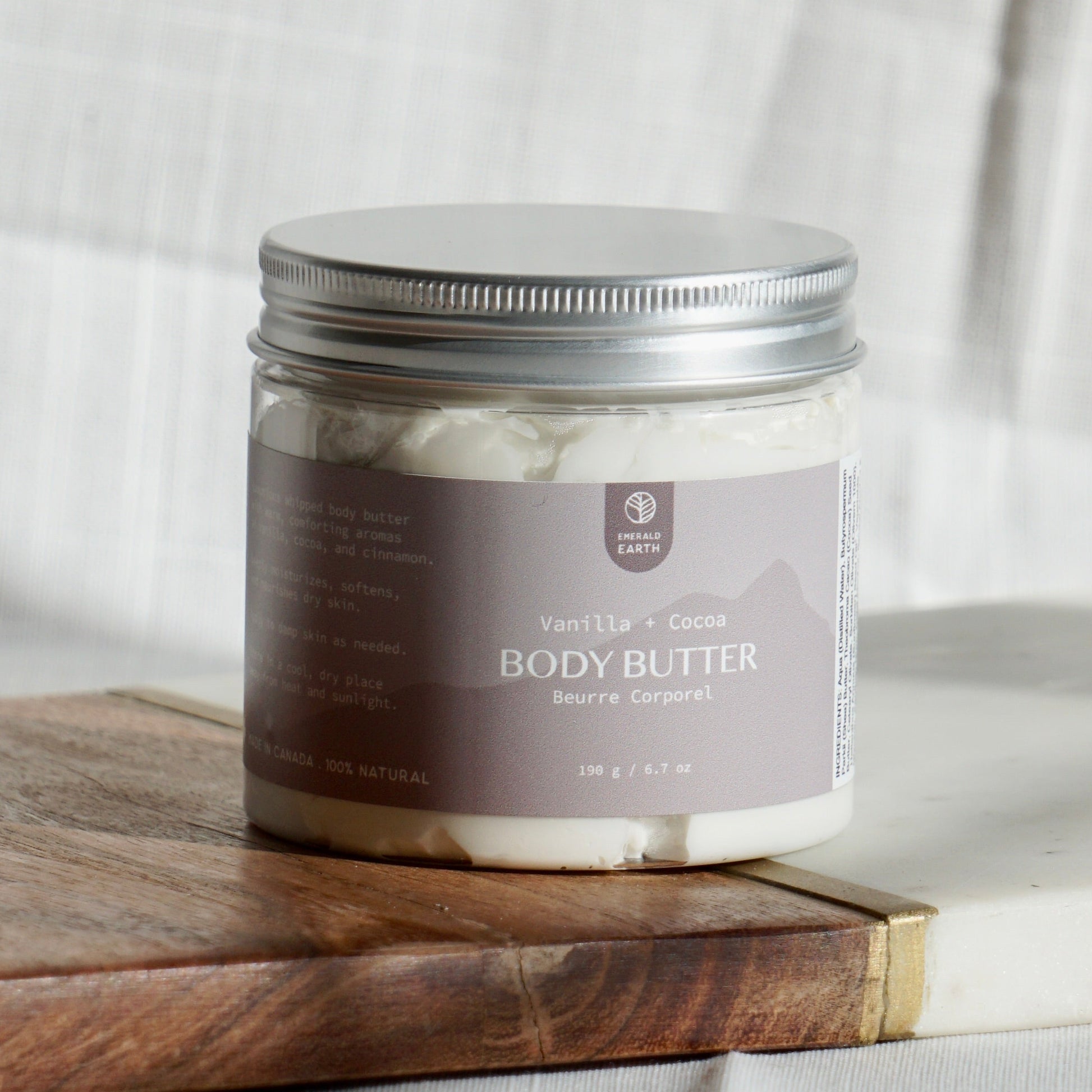 Jar of body butter on a wooden board with a white fabric background